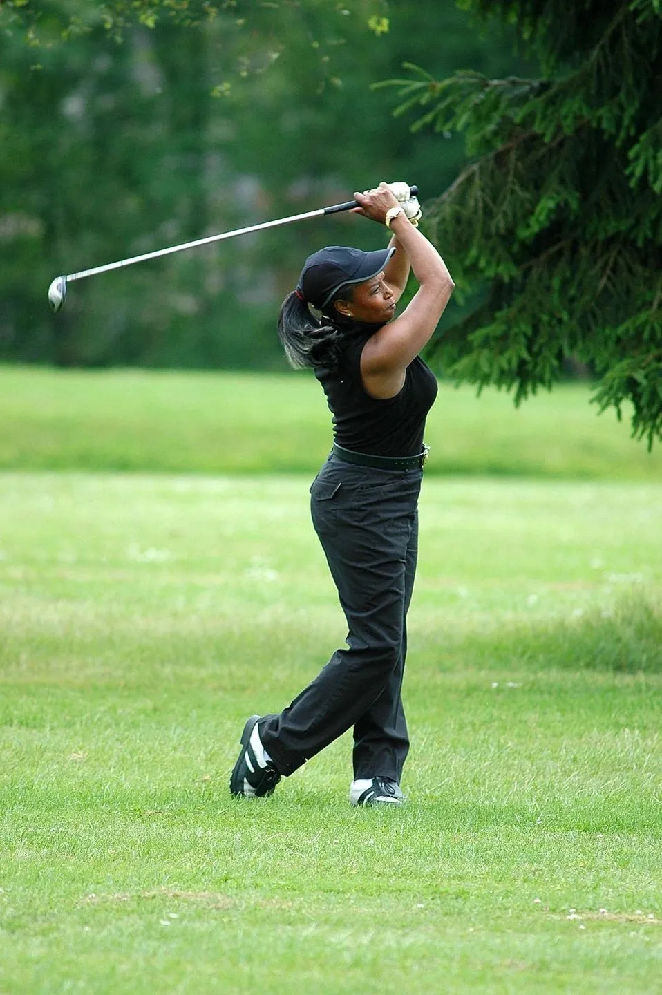 A woman swinging at the ball on a golf course.