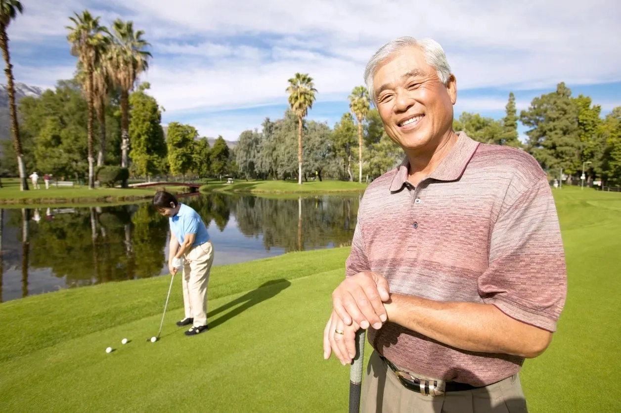 A man standing on top of a golf course holding onto two golf balls.