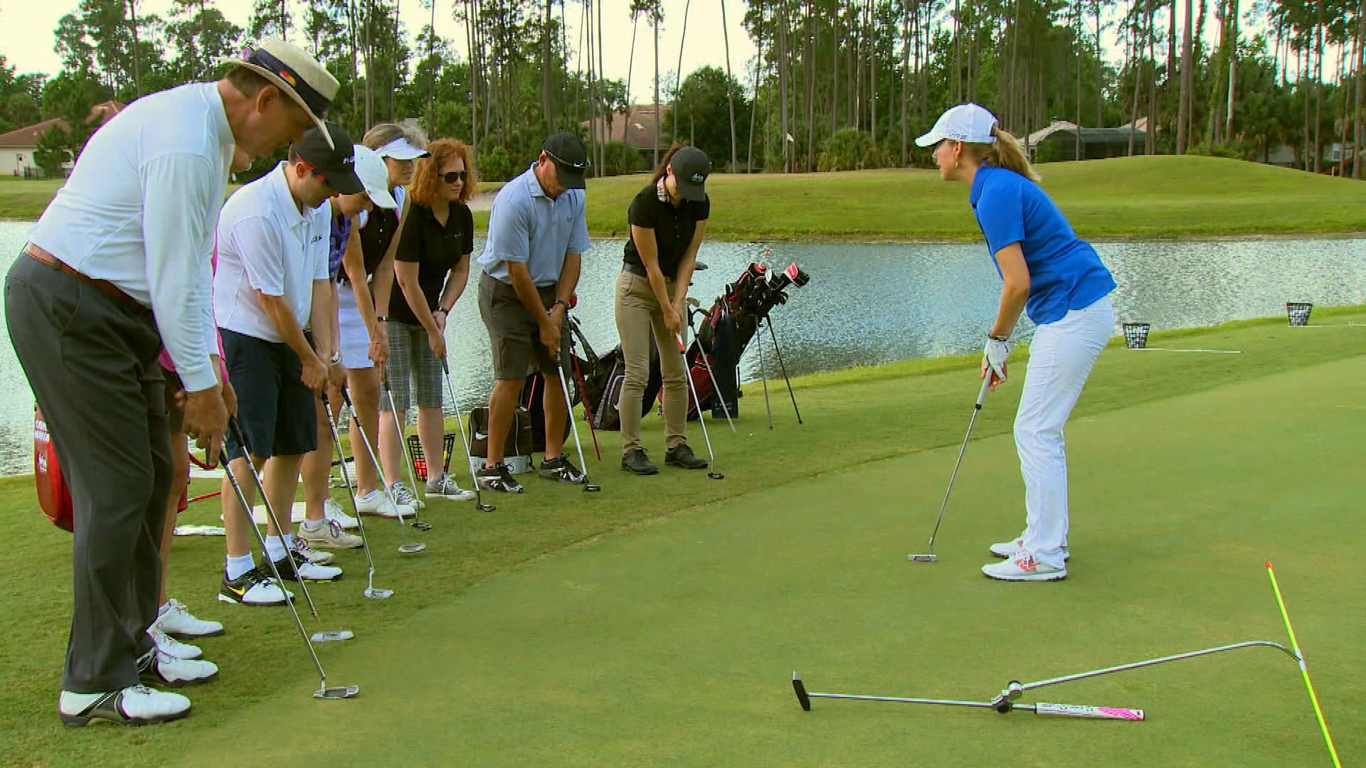 A group of people standing around on the golf course.