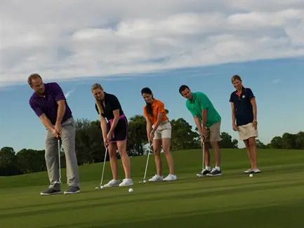 A group of people playing golf on the green.