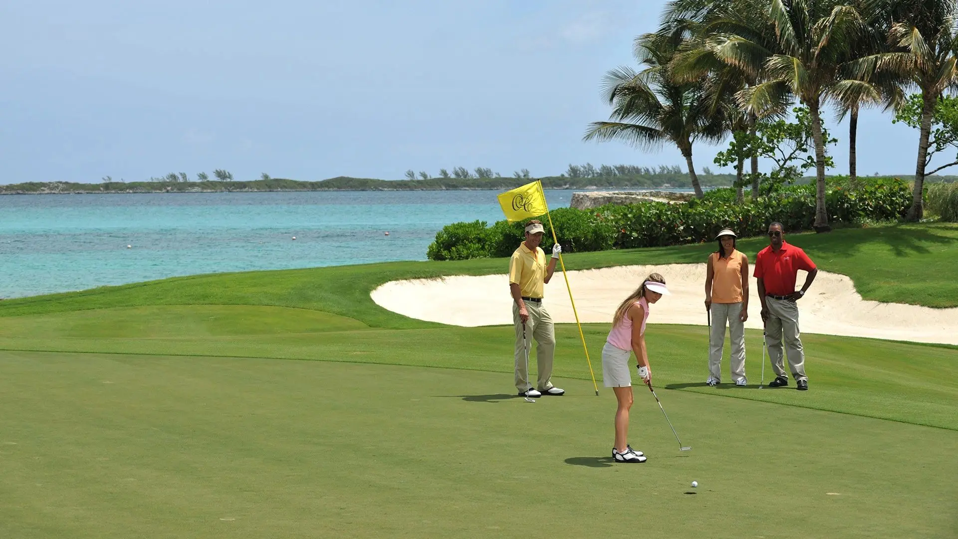 Three people are playing golf on a green.